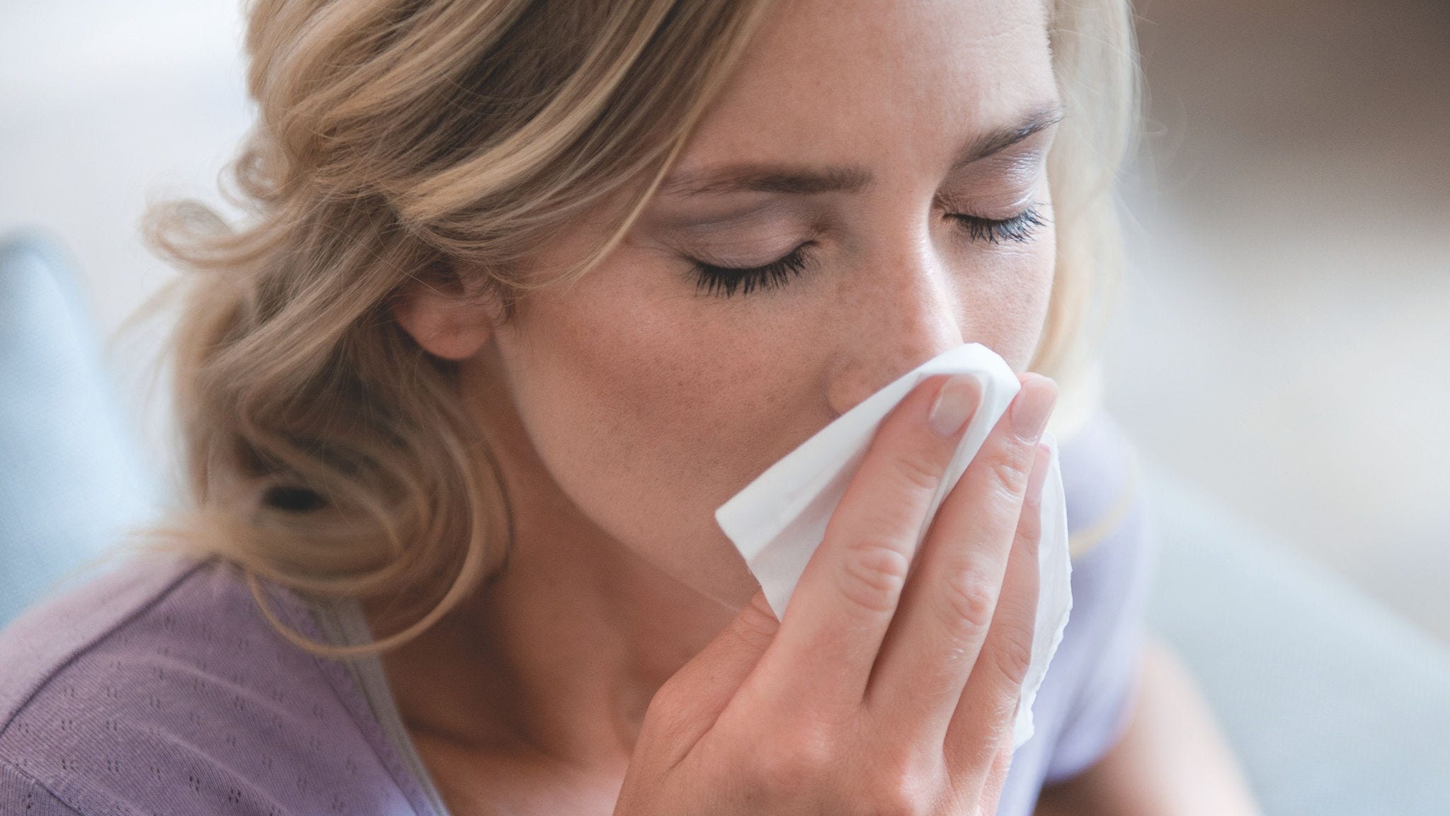 Donna che si soffia il naso per via di un’allergia ai pollini