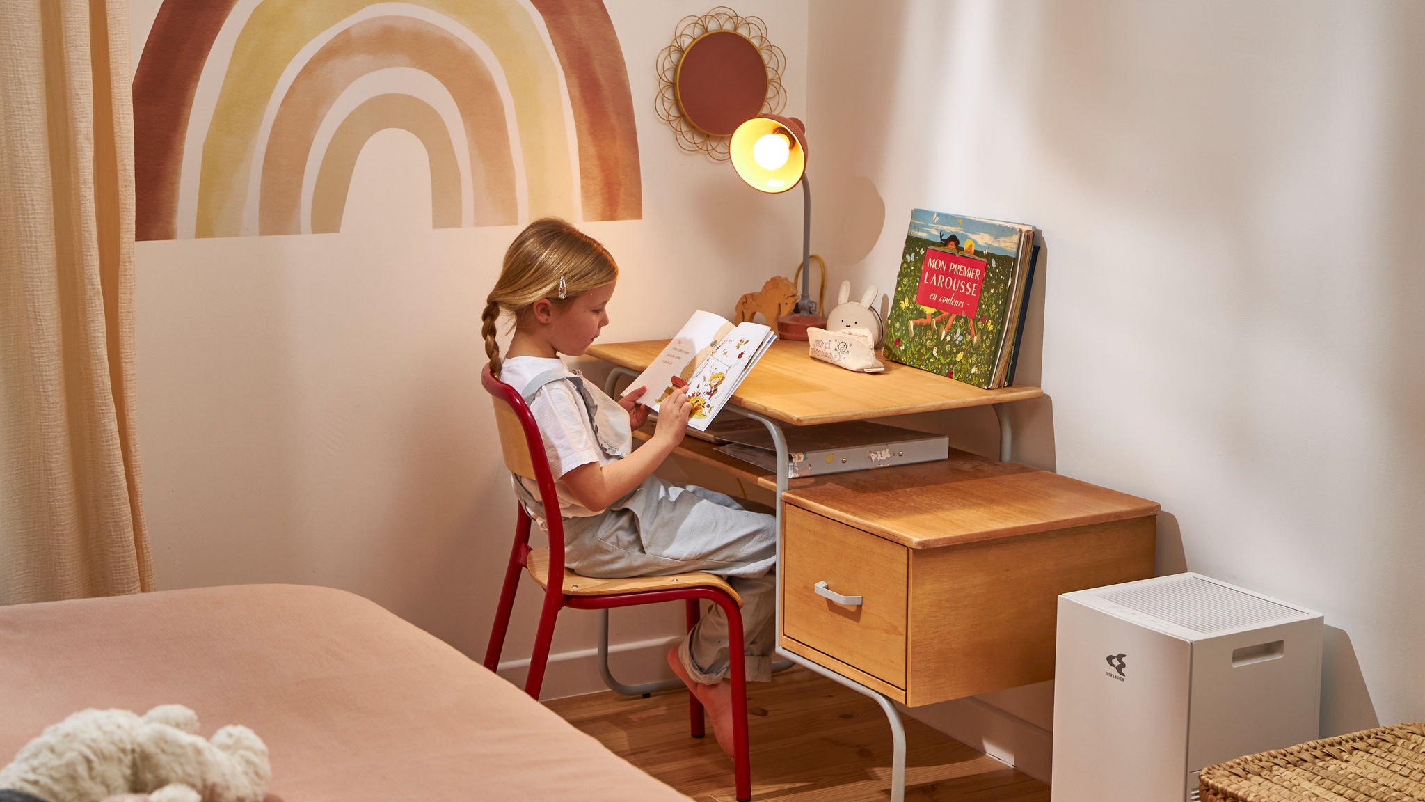 Una bambina legge un libro godendosi la qualità dell’aria fornita dal purificatore accanto alla sua scrivania