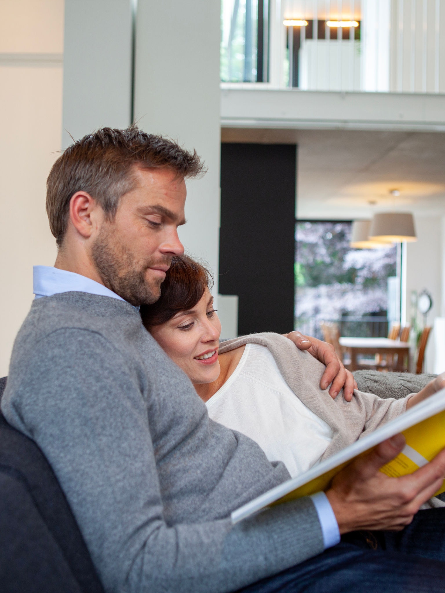 Coppia che legge un libro sul divano in dolce relax a una temperatura perfetta