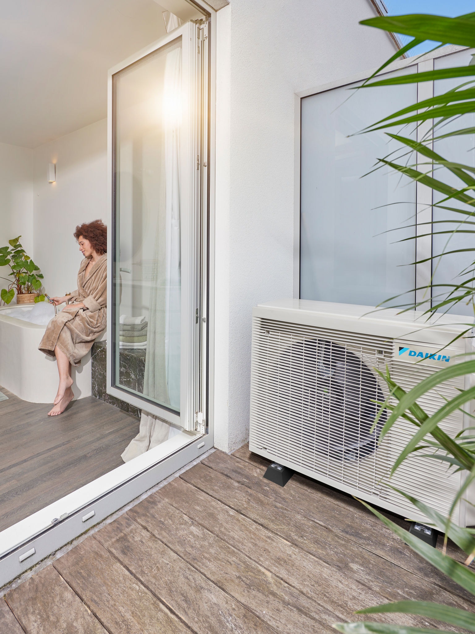 Pompa di calore ad aria installata accanto a una terrazza con le porte aperte su un bagno moderno