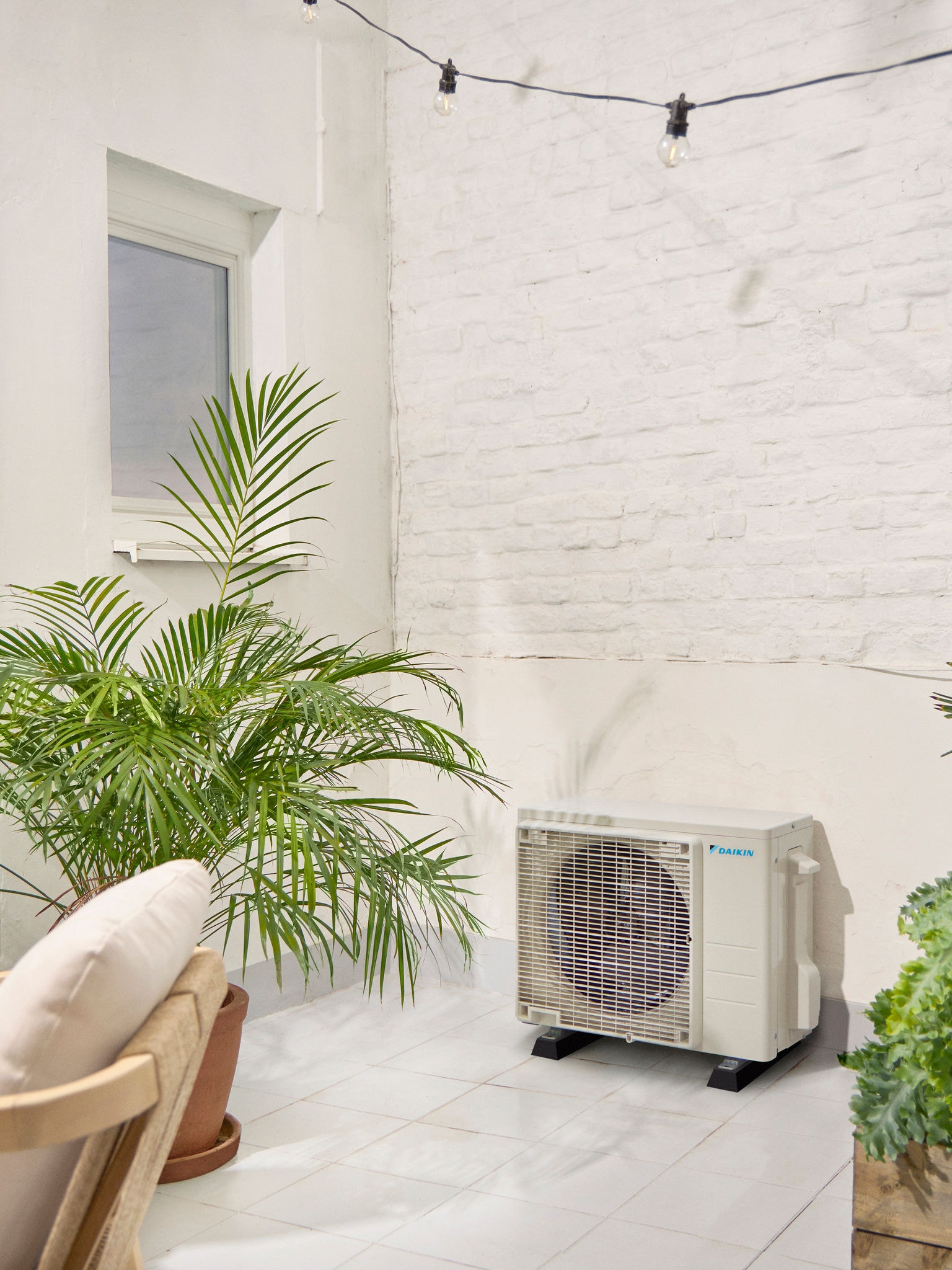 Unità esterna Daikin su una terrazza bianca con pianta