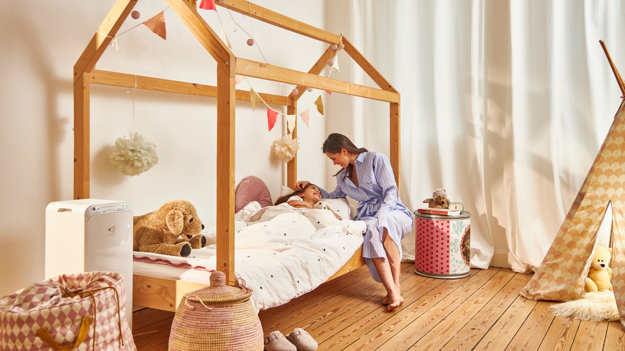 Madre che mette a letto la figlia in una casa sana grazie alla presenza del purificatore d'aria Daikin nella stanza