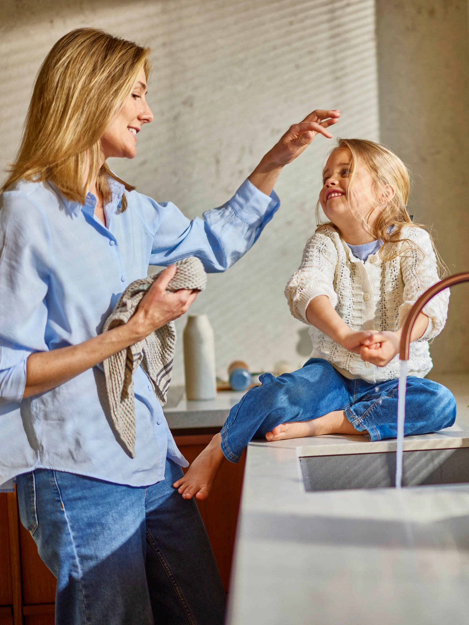 Una madre lava il viso al bambino con acqua tiepida in un bagno a basso consumo energetico