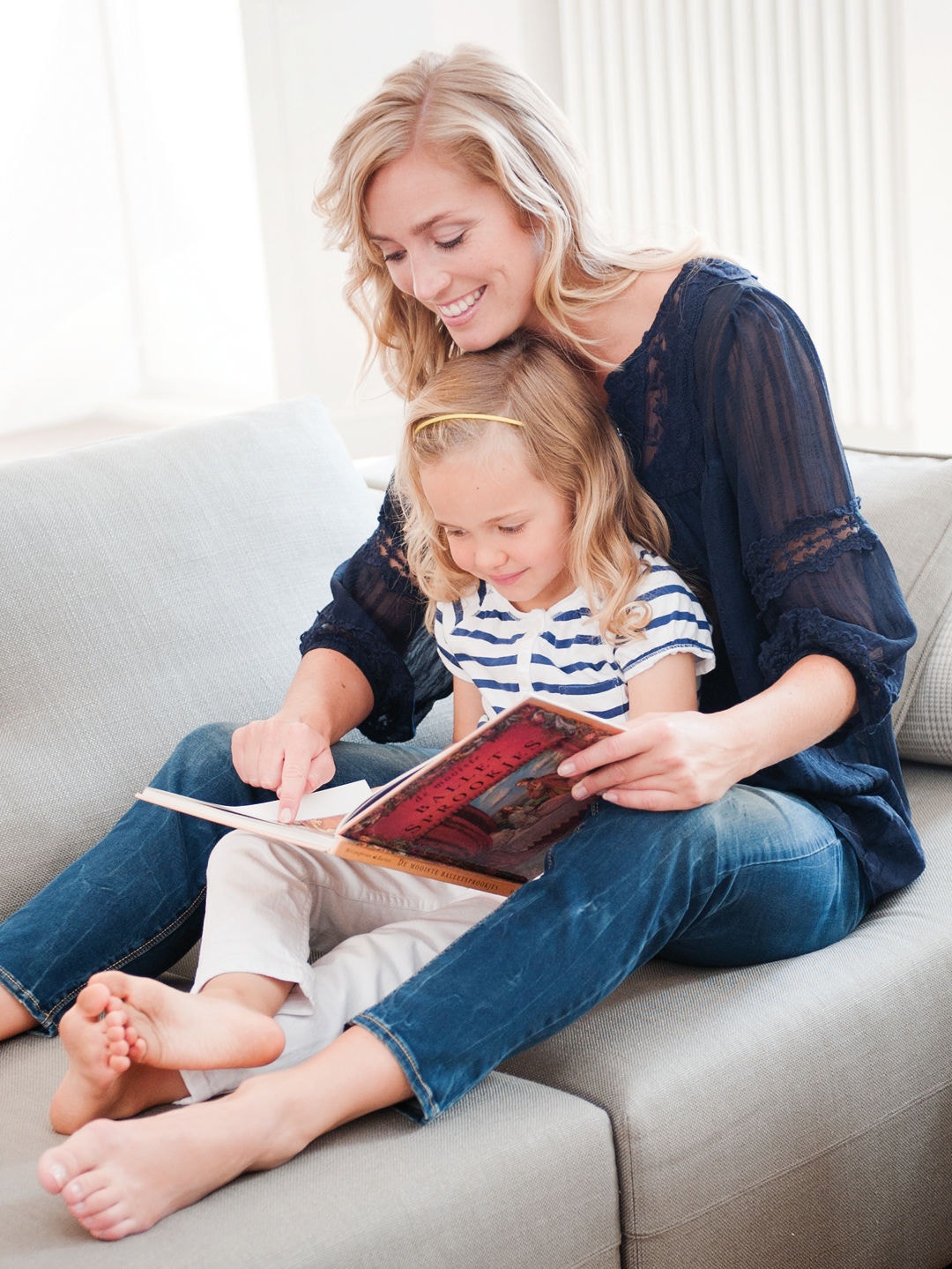 Una mamma legge un libro sul divano insieme a sua figlia