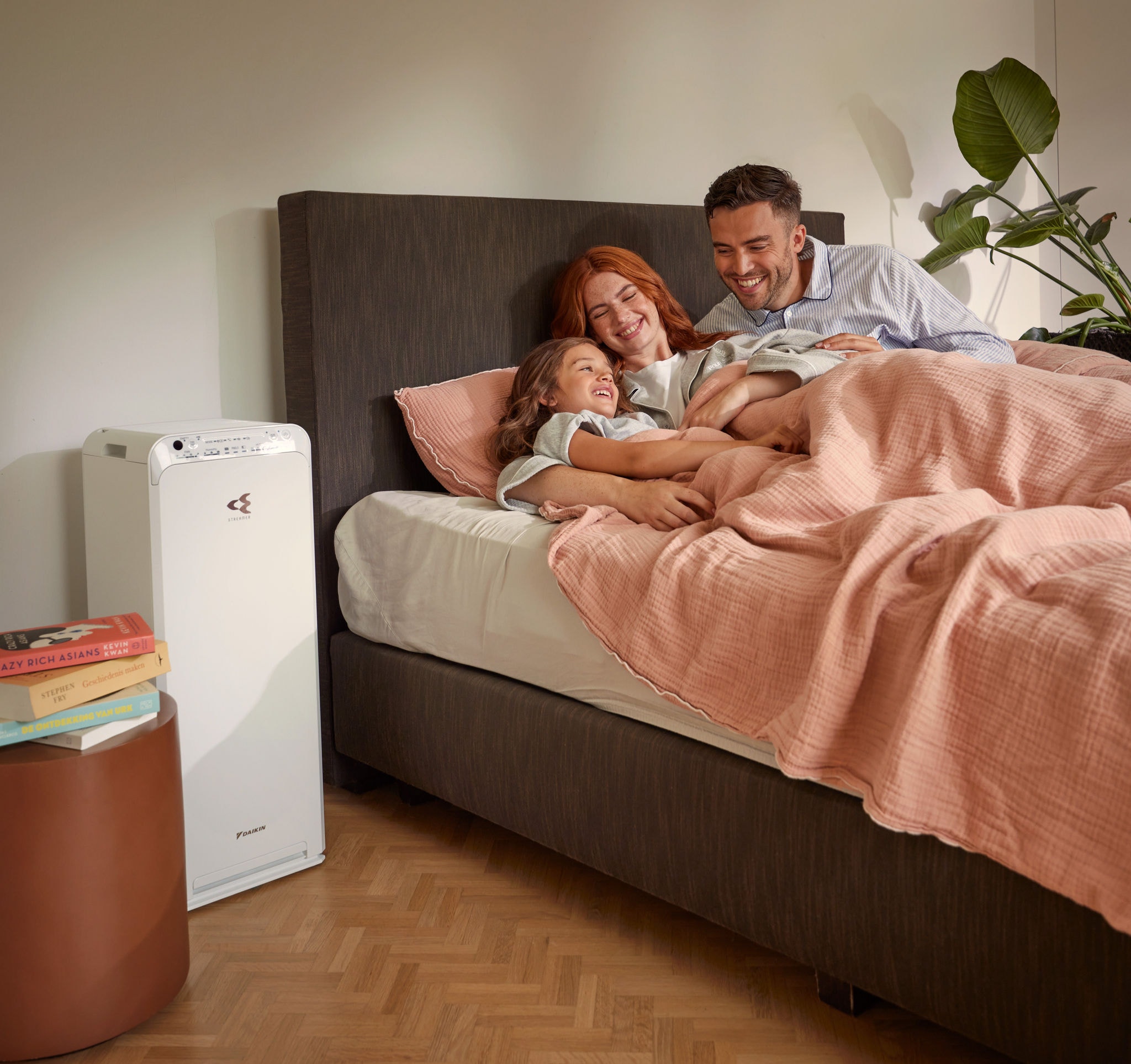 Una coppia si rilassa insieme al proprio bambino in camera da letto godendo dell’aria pulita offerta dal purificatore