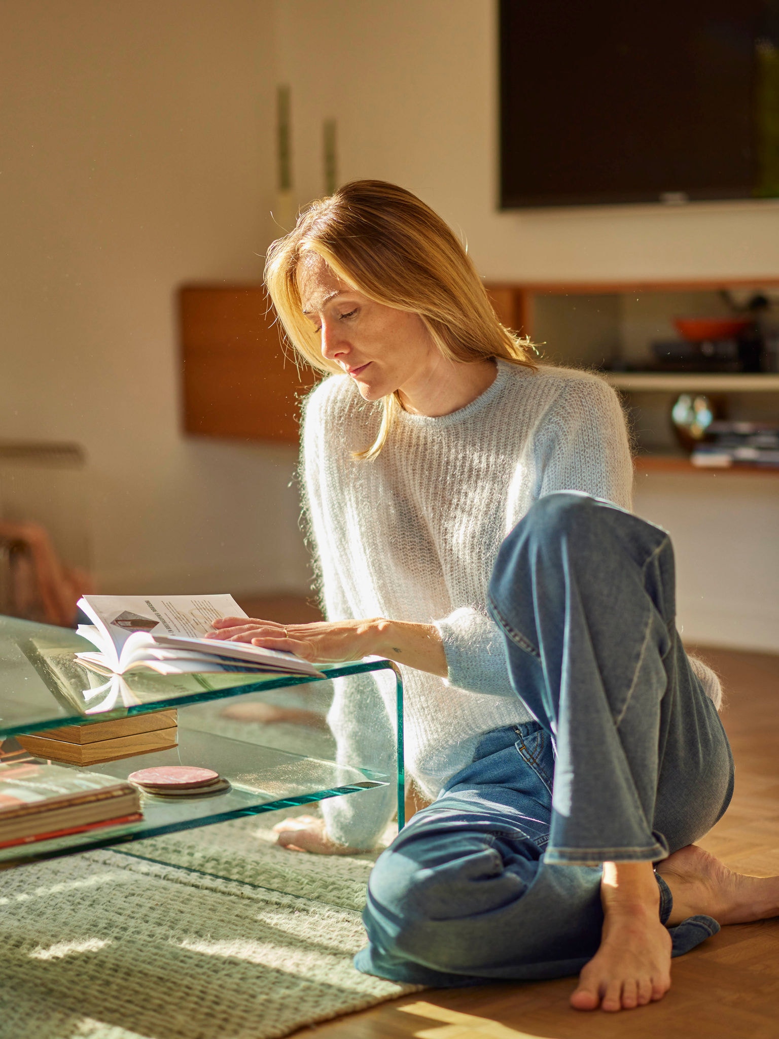 Una donna si rilassa con un libro in una casa efficiente dal punto di vista energetico, riscaldata con una pompa di calore