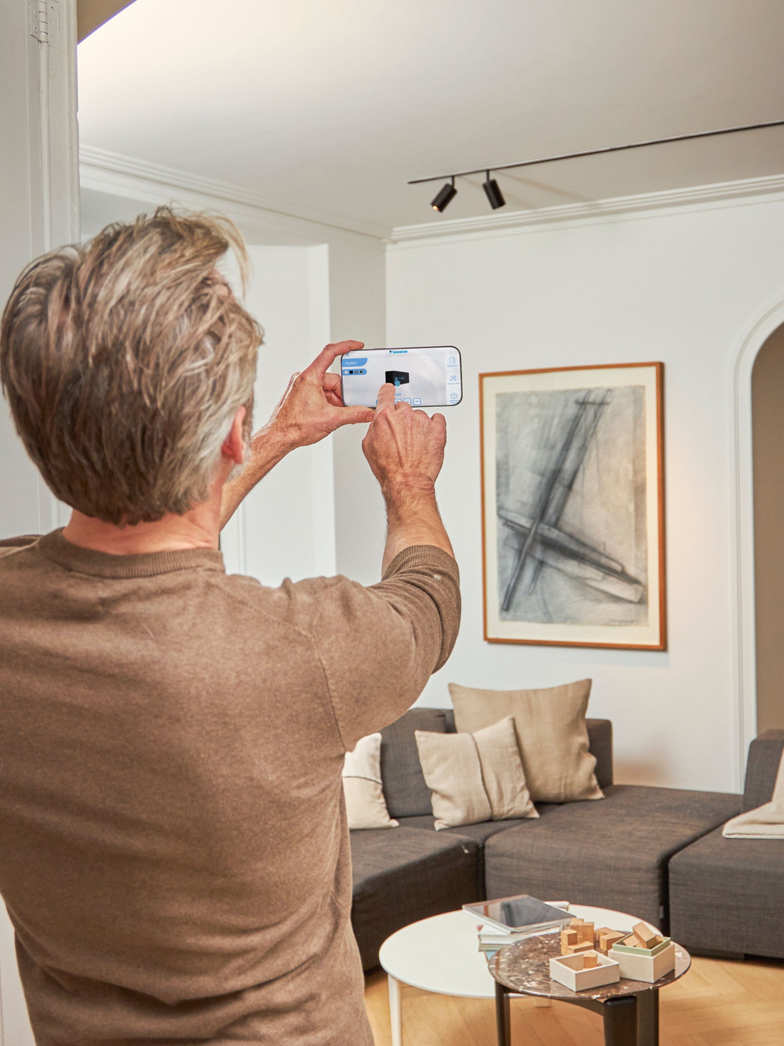 Un uomo mentre sta usando l'app 3D con realtà aumentata per visualizzare la pompa di calore aria-aria sia all'esterno che all'interno della sua casa