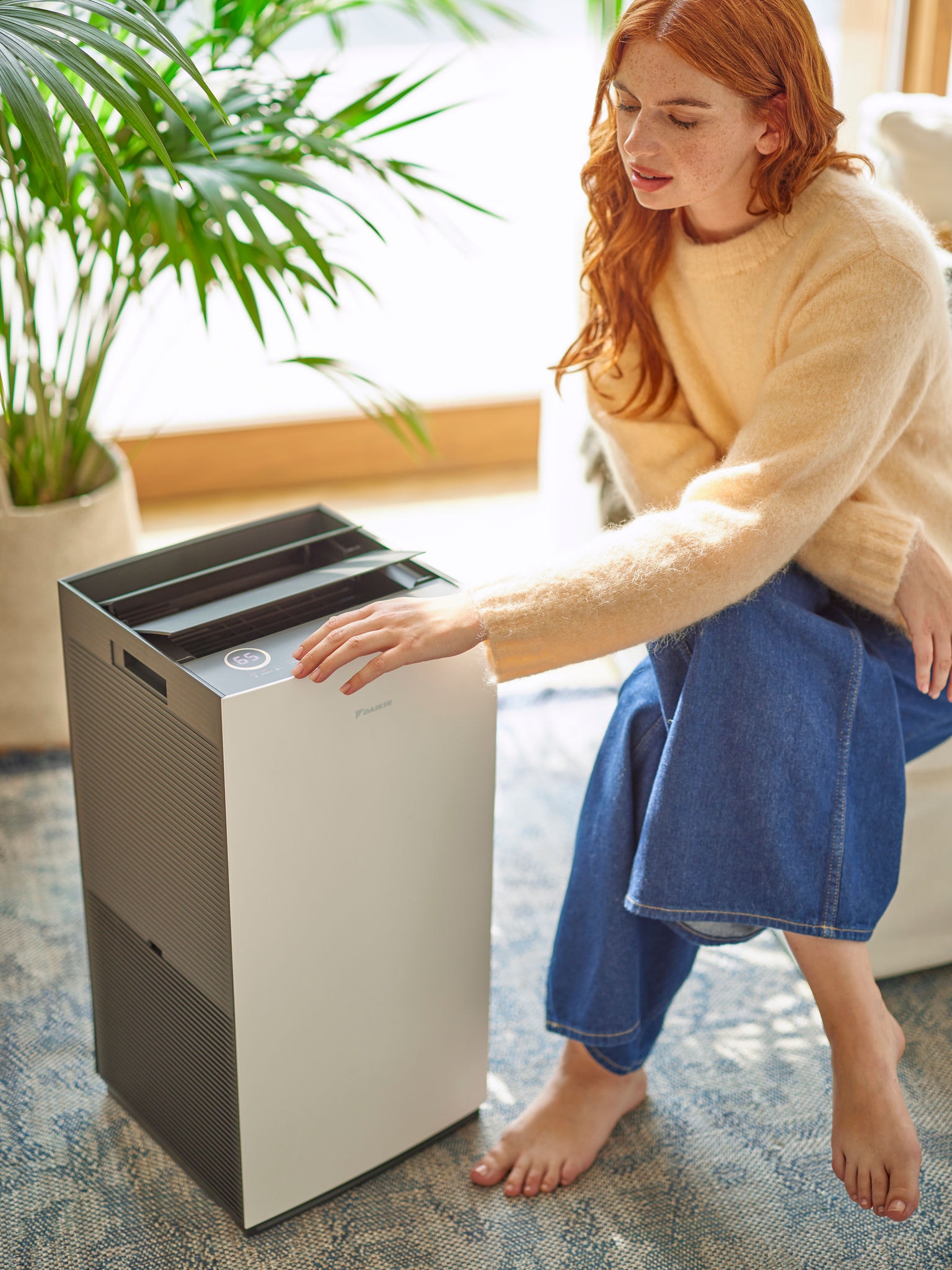 Una donna regola i comandi di un purificatore d'aria Daikin in una zona giorno