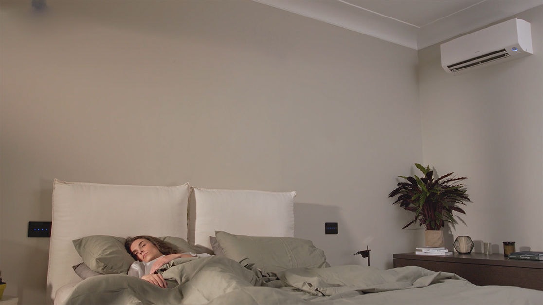 Una donna dorme serenamente con l’unità Daikin in modalità notturna silenziosa