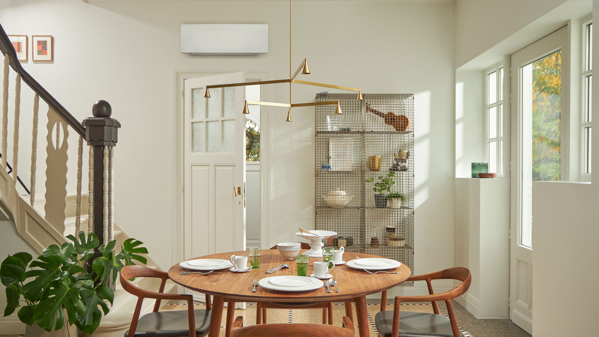 Ambiente con grande finestra, tavolo di legno e soluzione di climatizzazione nera, a parete