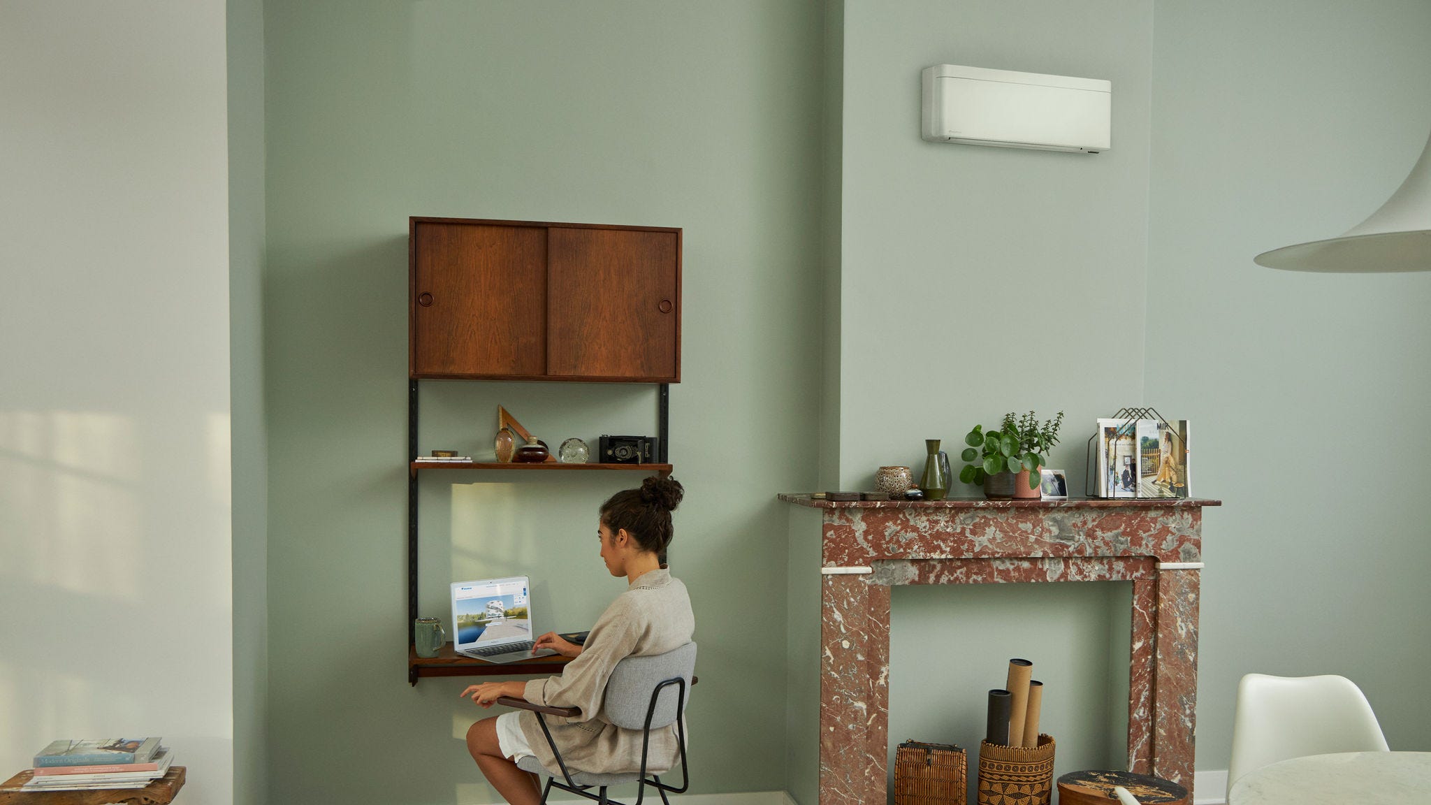 Una donna visita il Daikin Virtual Experience Centre con il suo laptop dalla sua scrivania in un salotto finemente arredato