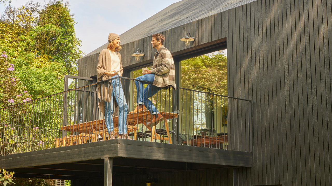 Una coppia chiacchiera sul terrazzo di un bungalow immerso nella natura